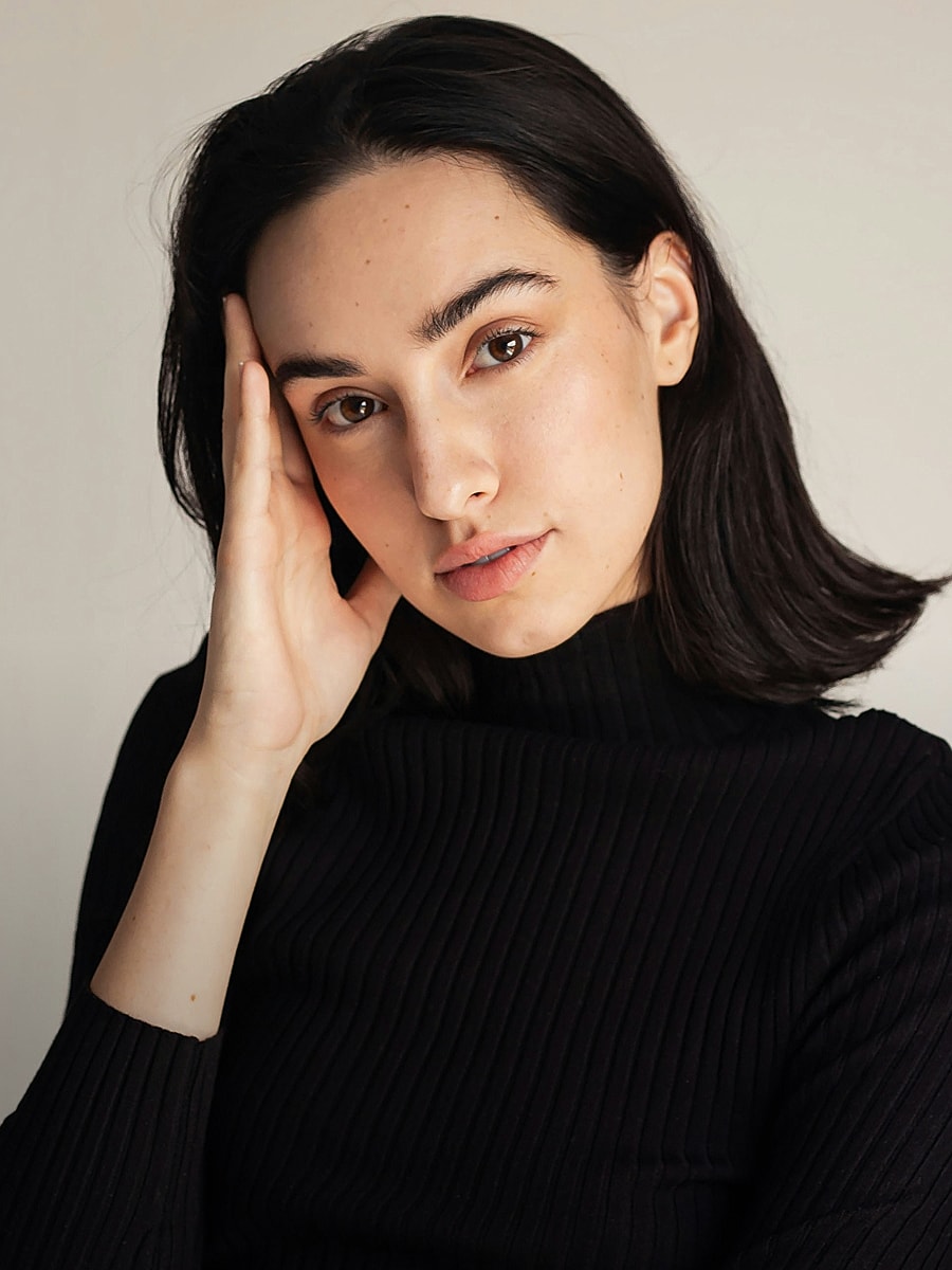 Woman in black turtleneck posing thoughtfully.