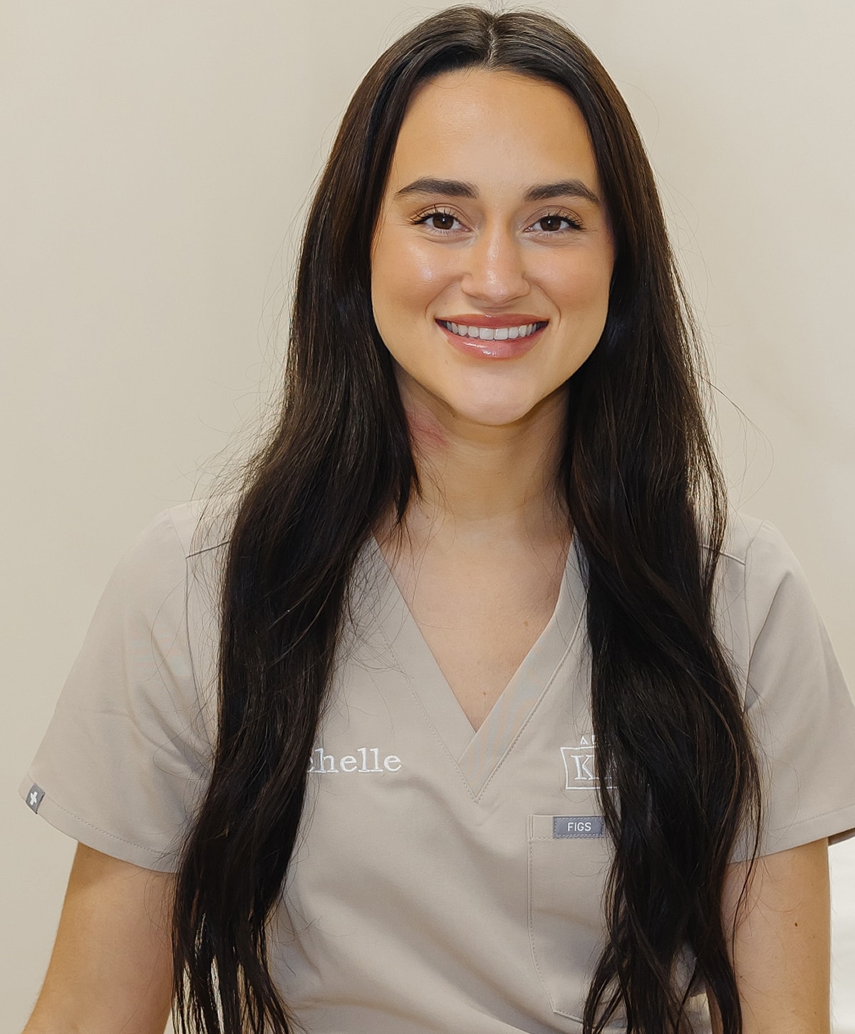 Young woman in medical scrubs smiling at camera.