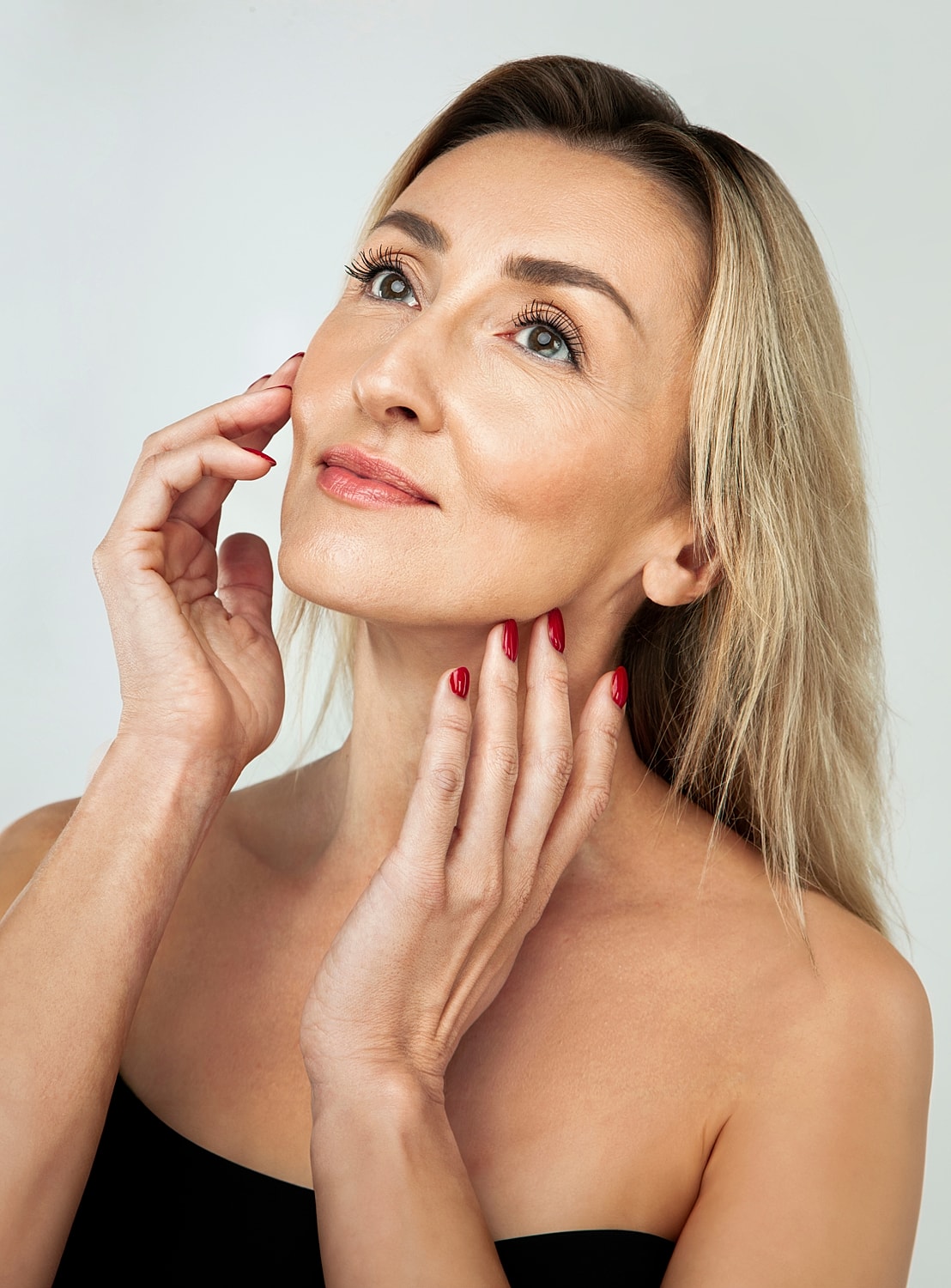 Woman with blonde hair touching her face.