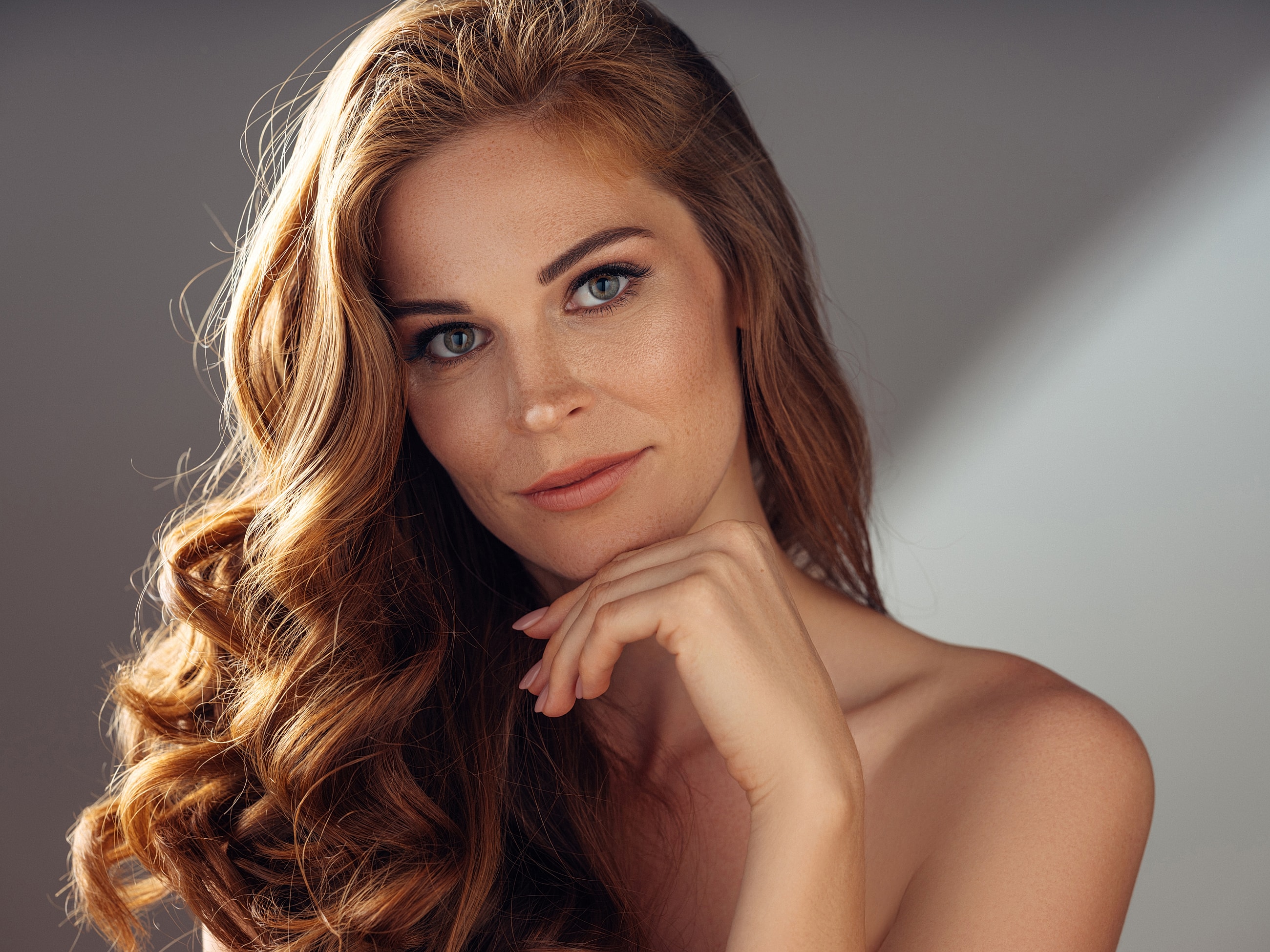 Woman with long, wavy hair and natural makeup.